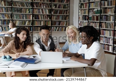 Diverse young teenage 18s friends students sit at desk in library use laptop prepare for exams, make collaborative task. Generation Z and modern tech usage for education and gaining new skills concept Royalty-Free Stock Photo #2139744867