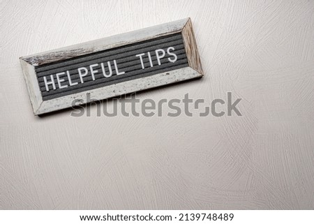 Helpful Tips text on a felt letterboard with wood frame and textured white background Royalty-Free Stock Photo #2139748489