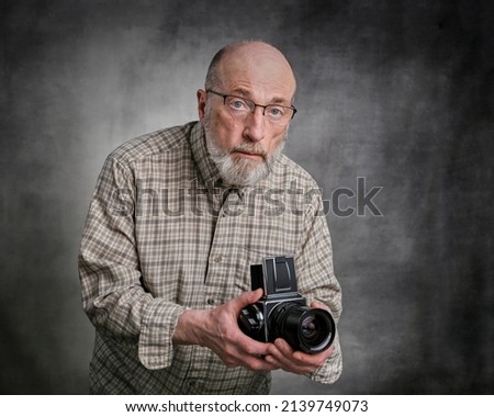portrait of a senior male photographer shooting pictures with a classic, medium format, film camera