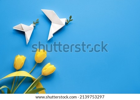 Dove of peace, paper origami. Peace to Ukraine. Yellow tulips, flowers, on blue background. Copy-space, place for text. Top view, flat lay, concept background. Royalty-Free Stock Photo #2139753297