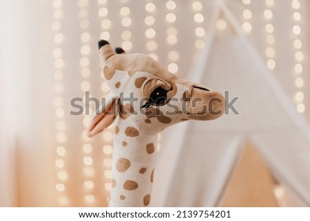 Children's plush toy giraffe on the background of garlands. Children's interior