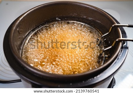 top view. oil boiling in a deep fryer. in the basket of the fryer cook shrimp in batter or potatoes. gadgets for the kitchen. cooking seafood in boiling vegetable oil. Royalty-Free Stock Photo #2139760541