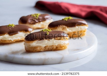 Chocolate Eclairs With Cream Filling And Pistachio Powder On Marble Serving Plate. Turkish name; Ekler.  Royalty-Free Stock Photo #2139782375