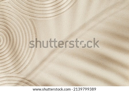 Zen garden meditation sandy background for relaxation. Lines drawing in sand and shadows of palm leaves. Concept of harmony, balance and meditation, spa, massage, relax. Top view and copy space. Royalty-Free Stock Photo #2139799389