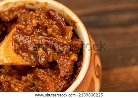 Stewed beans with meat in a small pot. A traditional rustic dish. Close-up, selective focus