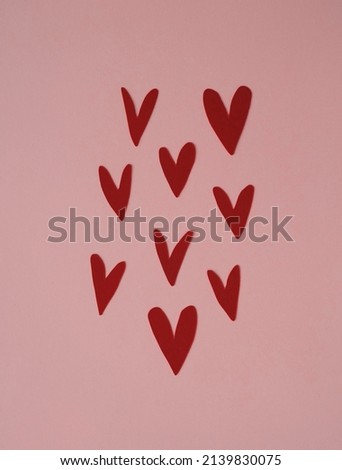 Simple Scandinavian Style Composition with Little Paper Hearts of Irregular Shape. Lovely Nursery Art with Red Love Symbols on a Light Blush Pink Background. Funny Infantile Style Design.