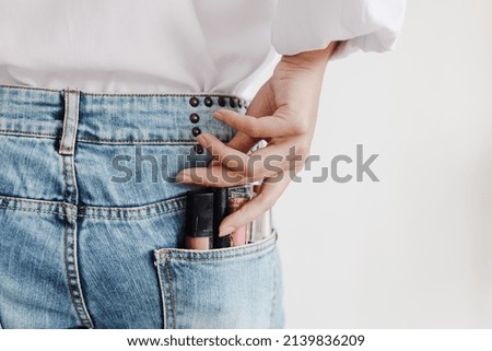 Set of lipsticks for make-up in jeans pocket held by manicured woman hand in casual style , studio shot isolated on white background with copy space