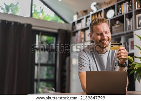 Smiling bearded man, ordering something online, using his credit card.