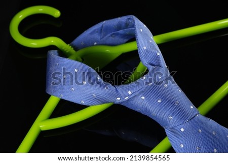 fashion necktie hanged on plastic hanger, neck tie on hanger with black background with tie knot