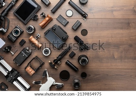 Short movie production essentials on wooden background with copy space. Different video making equipment for indie cinema production. Video production tools on brown table view from above.
