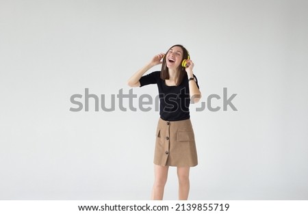 portrait of a young beautiful woman listening to music with yellow headphones on a white isolated background