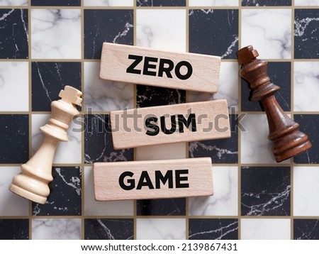 Two chess piece kings lying on the chessboard with the word zero sum game on a wooden block. Royalty-Free Stock Photo #2139867431