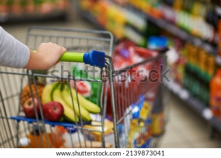 Stocking up on some essential supplies. Closeup shot of a woman pushing her trolley full of groceries in a supermarket.