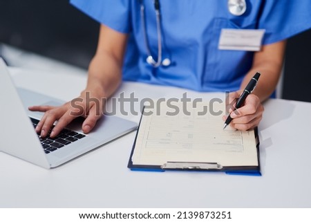 Keeping her records up to date. High angle shot of an unrecognizable female nurse filling out paperwork while sitting at her desk in the hospital. Royalty-Free Stock Photo #2139873251