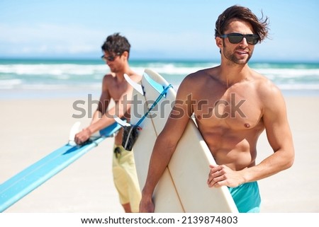 Surfs up. Two friends at the beach getting ready to head into the water for a surf. Royalty-Free Stock Photo #2139874803