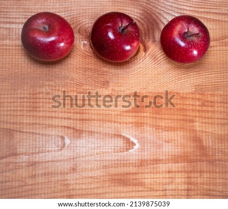 Top view on three red apples with raindrops on a wooden background with a place for text: rustic food, harvest gardening, ingredients for a healthy snack, soft focus, square image