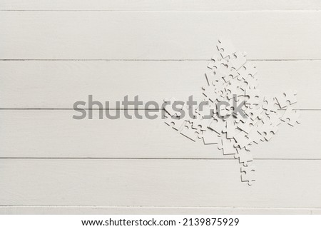 Maple leaf made of puzzle pieces on white wooden background. Canadian flag concept