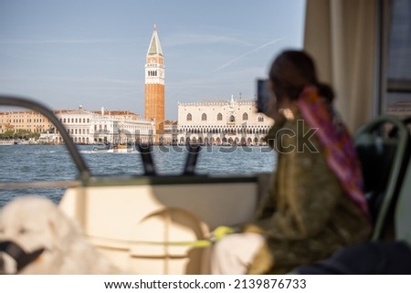 Woman in medical mask sitting in Vaporetto, famous water transportation in Venice. Taking photo of Venice. Concept of italian transportation during a pandemic. Idea of travel Italy