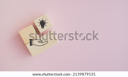 light bulb over hand icon on wood cubes block with pink background and copy space. New idea, solution, suggestion, Business review, strategy suggestion for business growth concept