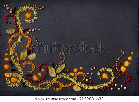 Pattern of spices on a black stone table. A set of spices from India. Decoration design. Various spices, peppers and herbs close-up top view. A set of peppers and spices for cooking. Royalty-Free Stock Photo #2139881633