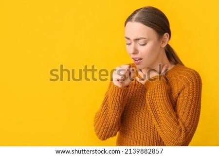 Ill coughing young woman with sore throat on yellow background