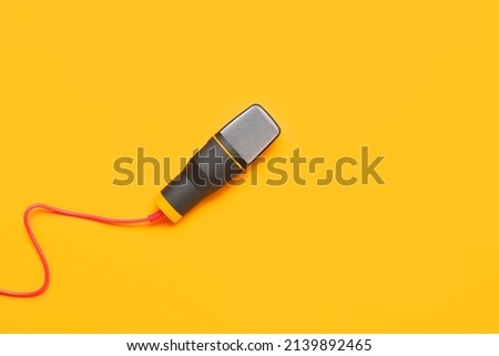 Modern microphone with wire on orange background