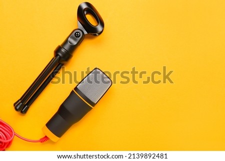 Modern microphone and stand on orange background