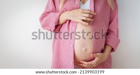 a pregnant woman in underwear and a pink shirt stands on a white background. High quality photo