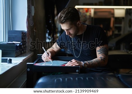 Caucasian tattoo artist  designing motifs on digital tablet  Royalty-Free Stock Photo #2139909469