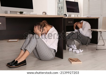 Scared employees hiding under office desks during earthquake Royalty-Free Stock Photo #2139927203