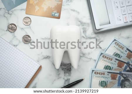 Flat lay composition with ceramic model of tooth and money on white marble table. Expensive treatment