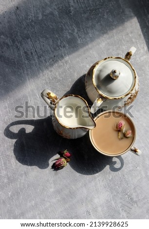 Vintage sugar bowl, milk jug and beautiful on light grey background. Shadows on a table. Close up photo of retro ceramic tableware. 