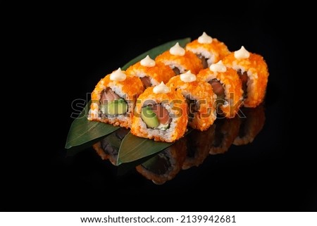Traditional delicious fresh sushi roll set on a black background with reflection. Sushi roll with rice, nori, cream cheese, tobiko caviar, avocado. Sushi menu. Japanese kitchen, restaurant. Asian food