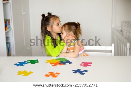 Girl sweetly kisses her little sister on the forehead as a sign of support and care. Psychological health of children with autism. Communication problems in special children. Colorful bright puzzles 
