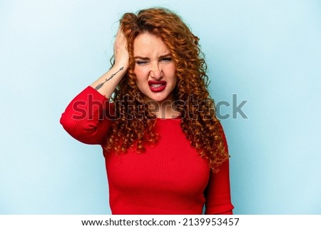 Young ginger caucasian woman isolated on blue background tired and very sleepy keeping hand on head.
