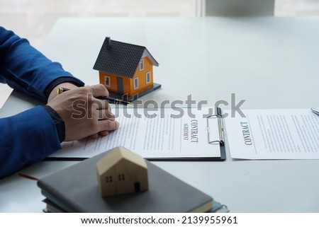 Real estate office home sales agents work with contract documents with house designs and calculators on the table.