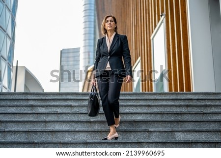 beautiful mature adult business woman in a suit walking in the finance district, confident and professional female lawyer going to the court of justice Royalty-Free Stock Photo #2139960695