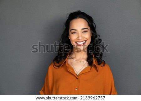 Portrait of happy latin young woman isolated on grey wall with copy space. Carefree hispanic woman smiling and looking at camera standing on gray background. Beautiful multiethnic girl laughing. Royalty-Free Stock Photo #2139962757