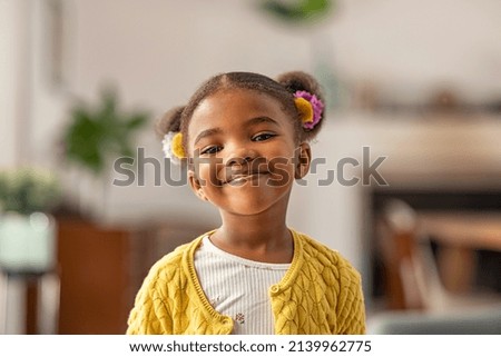 Smiling cute little african american girl with two pony tails looking at camera. Portrait of happy female child at home. Smiling face a of black 4 year old girl looking at camera with afro puff hair. Royalty-Free Stock Photo #2139962775