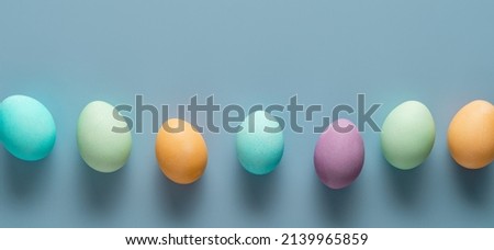 Easter holiday concept. Easter picture, multi-colored eggs, spring flowers on a light blue background. Happy Easter
