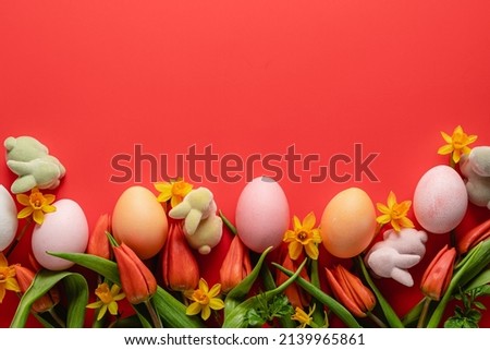 Easter holiday concept. Easter picture, multi-colored eggs, spring flowers on a red background. Happy Easter