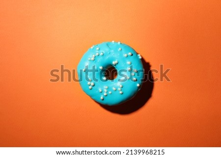 Delicious glazed doughnut on orange background, top view