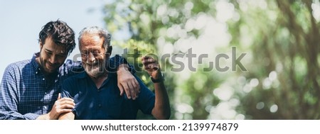 senior father with adult son in family concept banner background with copy space, elderly old man person are happy and enjoy with hipster son together by walking outdoor in nature Royalty-Free Stock Photo #2139974879