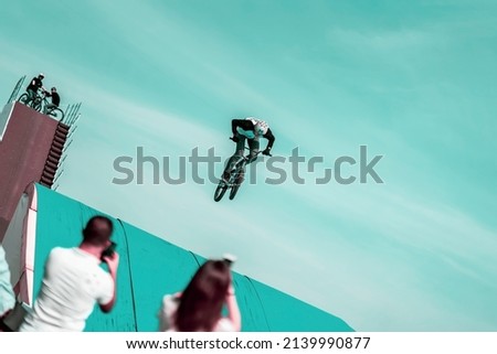 Extreme unrecognizable cyclist, young man doing jump with bmx bike on background of sky. Intentional angle to the horizon, increasing exciting flight risks Royalty-Free Stock Photo #2139990877