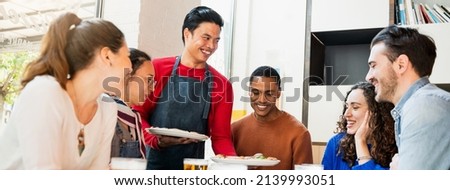 Horizontal banner or header Young smiling Philippine waiter bringing pizzas to a group young happy friends.