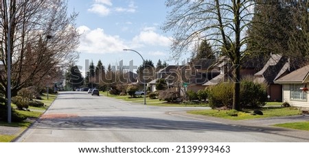 Residential neighborhood Street in Modern City Suburbs. Sunny Winter Day. Fraser Heights, Surrey, Greater Vancouver, British Columbia, Canada. Royalty-Free Stock Photo #2139993463