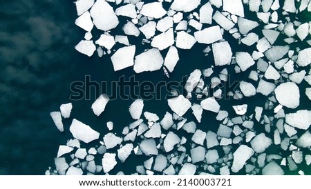 Kayak sailing between ice floes on the lake. Aerial drone view. Abstract nature background. Baikal lake, Siberia, Russia. Spring landscape Royalty-Free Stock Photo #2140003721