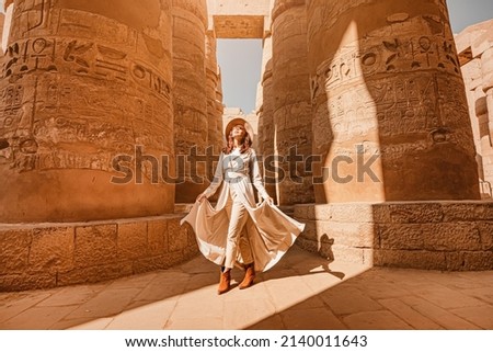 Woman traveler explores the ruins of the ancient Karnak temple in the city of Luxor in Egypt. Great row of columns with carved hieroglyph Royalty-Free Stock Photo #2140011643