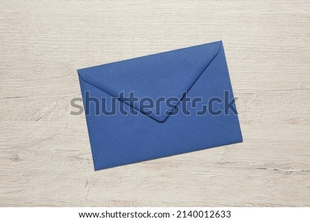 Blue envelope on white wooden table, top view