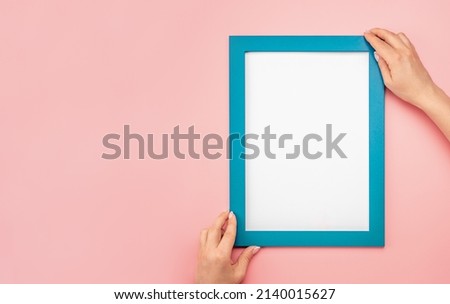 Woman hold blank diploma frame on pink wall background. Hanging photo frame mockup on pink wall. Picture frame mockup. Holding frame. Female hands hold mockup with white paper. copy space